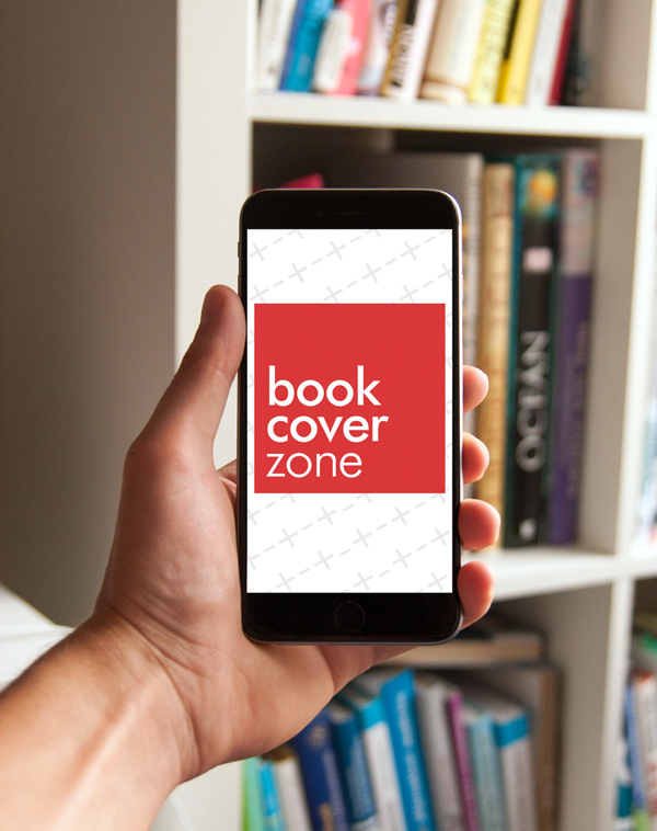 Man Holding Black iPhone on Bookshelf